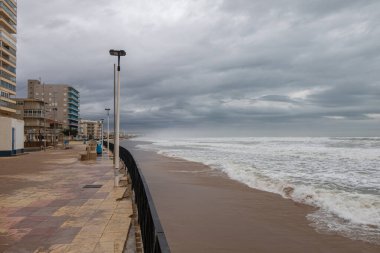 Kumsalda fırtına dalgalanması ve bulutlu gökyüzü