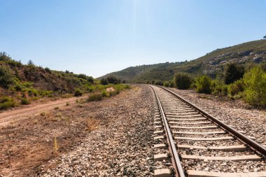 Güneşli bir sabahta konuksever olmayan ve kurak bir yerden geçen yalnız tren yolu.. 