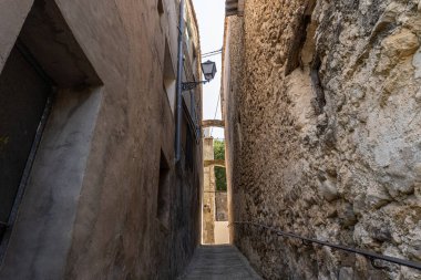 Çok dar bir sokak, tepesinde bir sokak lambası ve kemerler var.. 