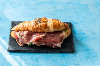 Serrano jambonuyla doldurulmuş kruvasan, marul, susam ve haşhaş tohumu..