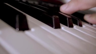 Müzikal klavyenin tuşlarını çalan bir elin yakın çekimi