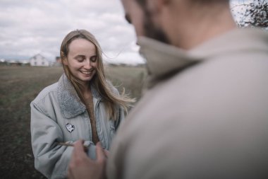 Birbirine aşık bir çift, bulutlu bir havada açık soya fasulyesi tarlasında yürür ve bol bol sarılır.