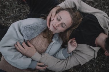 Birbirine aşık bir çift, bulutlu bir havada açık soya fasulyesi tarlasında yürür ve bol bol sarılır.