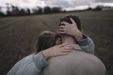 Birbirine aşık bir çift bulutlu bir havada soya fasulyesi tarlasında yürür.