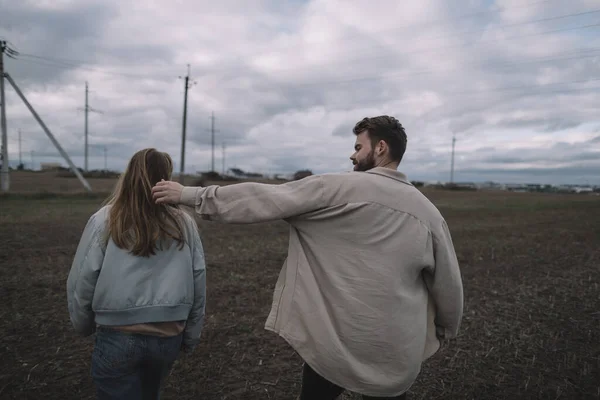 Um casal apaixonado caminha em um campo de soja aberto à noite em tempo nublado — Fotografia de Stock