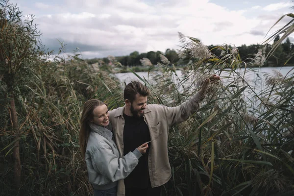 Un couple aimant se tient dans les roseaux sur fond de lac le soir et communique — Photo