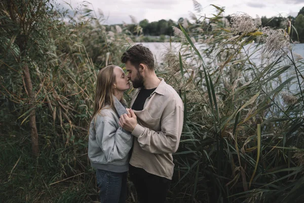 Un couple aimant se tient dans les roseaux sur fond de lac le soir et communique — Photo