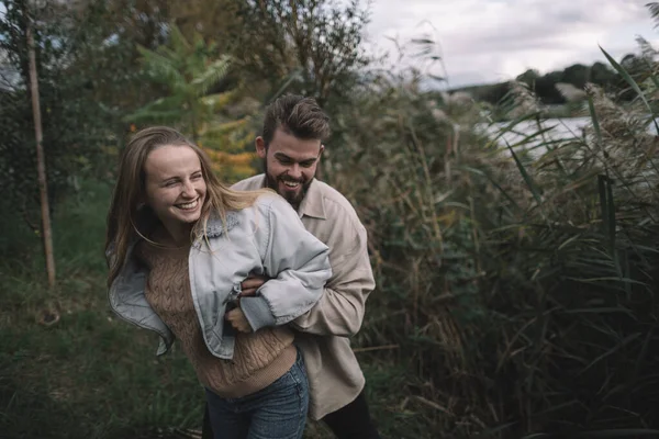 Una pareja amorosa se encuentra en las cañas contra el telón de fondo de un lago por la noche y se comunica —  Fotos de Stock