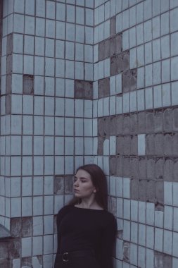 Korkuyla köşeye sıkıştırılan kız duruyor, bakıyor ve ellerini kıvırıyor.