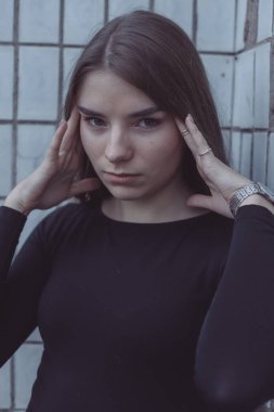 Korkuyla köşeye sıkıştırılan kız duruyor, bakıyor ve ellerini kıvırıyor.