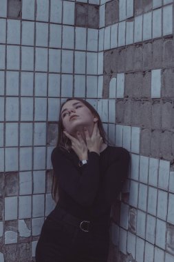 Korkuyla köşeye sıkıştırılan kız duruyor, bakıyor ve ellerini kıvırıyor.