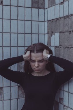 Korkuyla köşeye sıkıştırılan kız duruyor, bakıyor ve ellerini kıvırıyor.