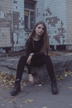 Genç kız oturuyor ve yıkılmış Sovyet duvarının arka planına bakıyor.