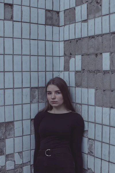 Korkuyla köşeye sıkıştırılan kız duruyor, bakıyor ve ellerini kıvırıyor.