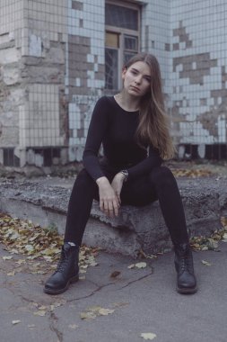 Genç kız oturuyor ve yıkılmış Sovyet duvarının arka planına bakıyor.