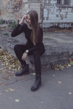 Genç kız oturuyor ve yıkılmış Sovyet duvarının arka planına bakıyor.