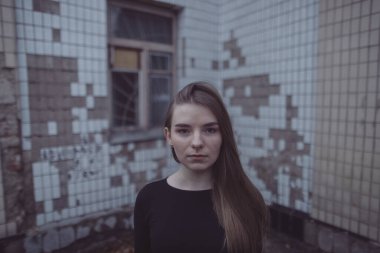 Korkuyla köşeye sıkıştırılan kız duruyor, bakıyor ve ellerini kıvırıyor.