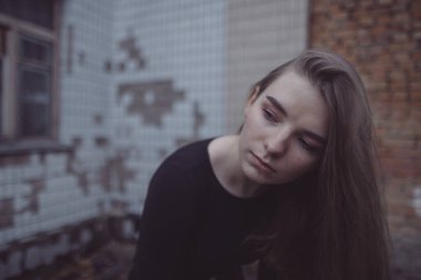 Korkuyla köşeye sıkıştırılan kız duruyor, bakıyor ve ellerini kıvırıyor.