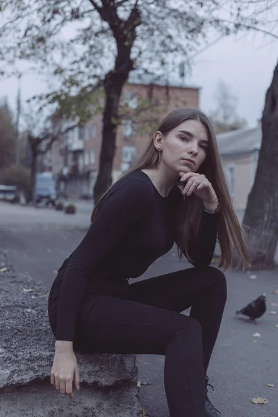 Genç kız oturuyor ve yıkılmış Sovyet duvarının arka planına bakıyor.