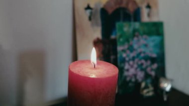 Mum resimlerin arka planında ve beyaz bir duvarda yanıyor.