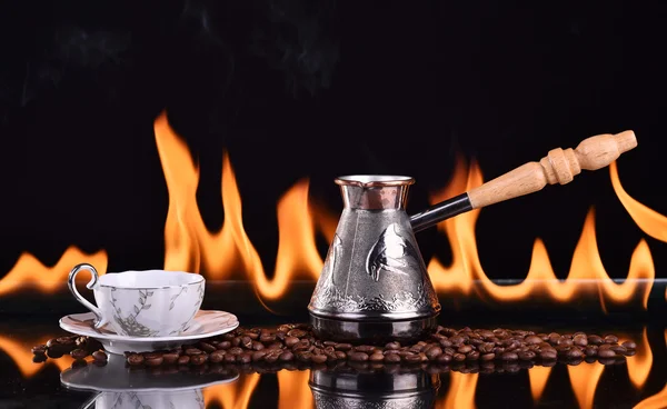 Уволенная чашка кофе с кофейными зёрнами и турком на тёмном фоне — стоковое фото