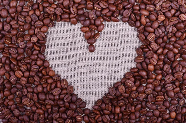 Srdce s kávová zrna na prádlo textury stůl — Stock fotografie