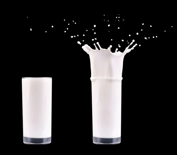 Weiße Frischmilchspritzer im Glas auf schwarzem Hintergrund — Stockfoto