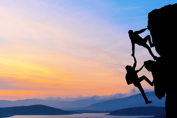 El trabajo conjunto en equipo de dos hombres viajeros se ayudan mutuamente en la parte superior de un equipo de escalada, un hermoso paisaje al atardecer — Foto de Stock