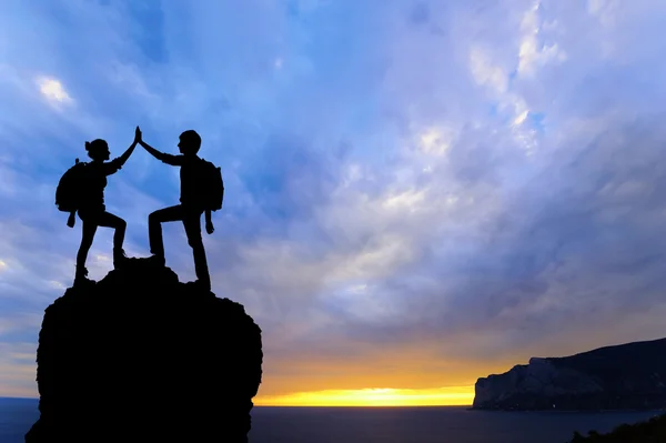 İki kişi adam kız başarı dağ tepe üzerinde silüeti. Spor ve aktif bir yaşam günbatımı manzara