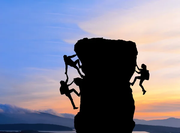 The joint work teamwork of two men travelers help each other on top of a mountain climbing team, a beautiful sunset landscape — Stock Photo, Image