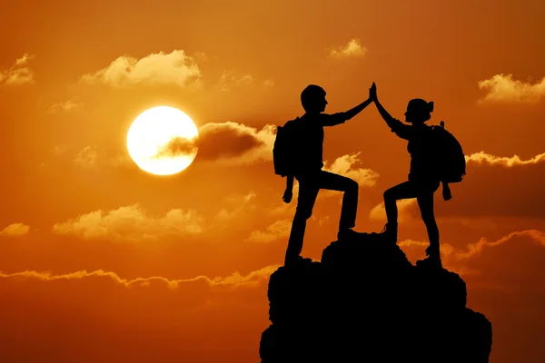 İki kişi adam kız başarı dağ tepe üzerinde silüeti. Spor ve aktif bir yaşam günbatımı manzara