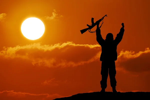 Askeri asker veya memur batımında silahlarla silüeti. atış, elinde silah, renkli gökyüzü, dağ, arka plan Stok Fotoğraf