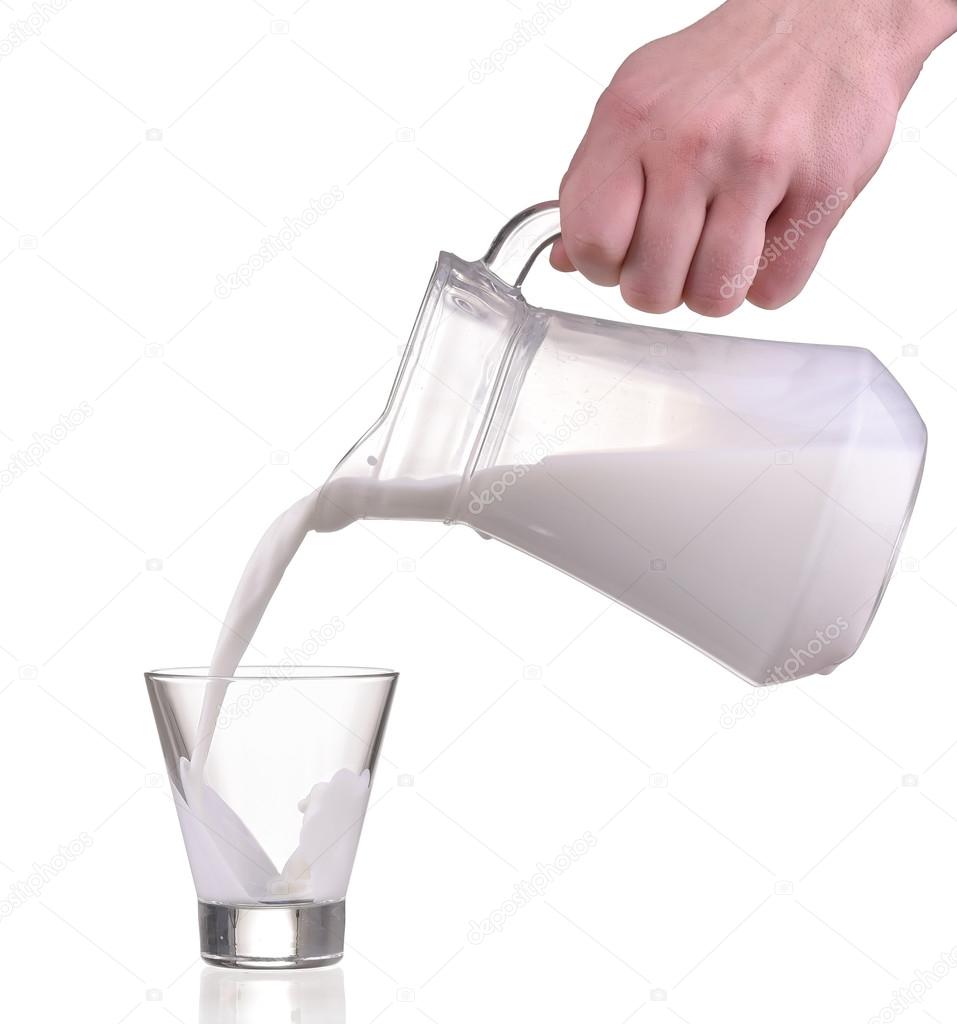 Pouring milk from jug bottle in a glass on white background — Stock