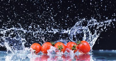 Su damlaları makro üzerinde kırmızı kiraz domates düşmek ve sıçrama yapmak