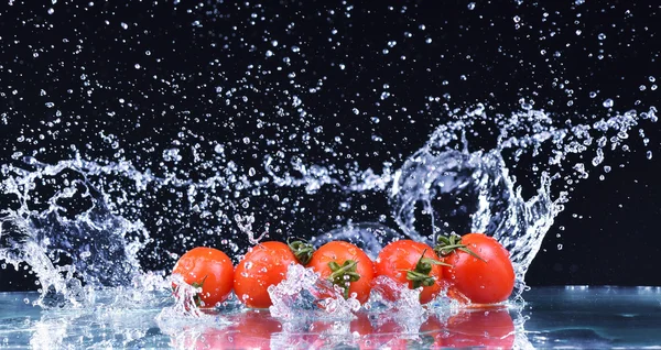 Macro drops of water fall on the red cherry tomatoes and make splash — Stock Photo, Image