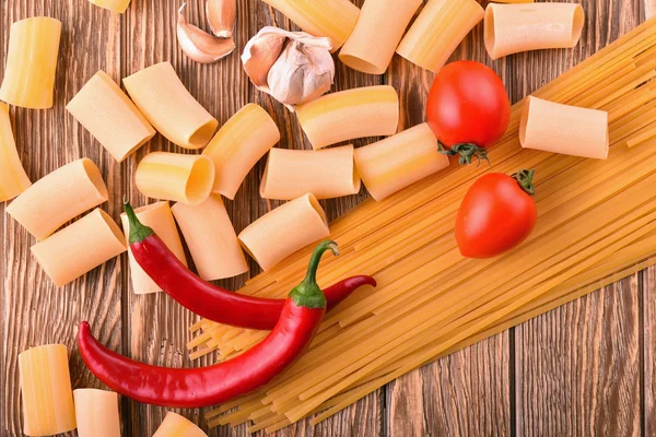 Macarrão macarrão pimenta tomate cereja alho na mesa de madeira na cozinha — Fotografia de Stock