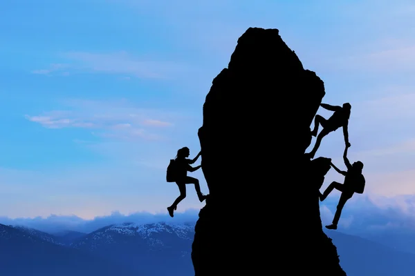 The joint work teamwork of two men travelers and girl help each other on top of a mountain climbing team, a beautiful sunset landscape — Stock Photo, Image