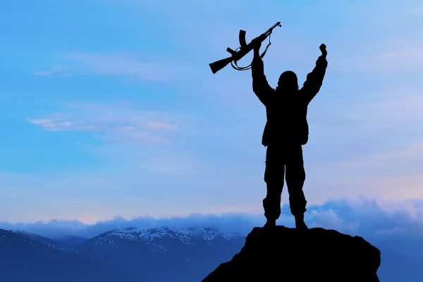 军事士兵或军官与武器在日落时的剪影。射击，拿着枪，色彩斑斓的天空，山，背景 — 图库照片