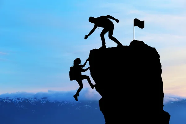 Die gemeinsame Arbeit von zwei Menschen, die sich gegenseitig helfen, an der Spitze eines Bergsteigerteams, einer wunderschönen Sonnenuntergangslandschaft. — Stockfoto