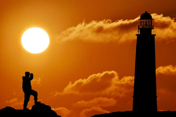 Silhouette of military soldier or officer with weapons at sunset see to lighthouse. shot, holding gun, colorful sky, mountain, background — Stock Photo, Image