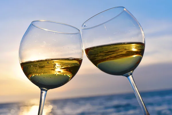 Romántica copa de vino sentada en la playa al atardecer Copas de vino blanco contra el atardecer, vino blanco sobre el fondo del cielo con nubes — Foto de Stock