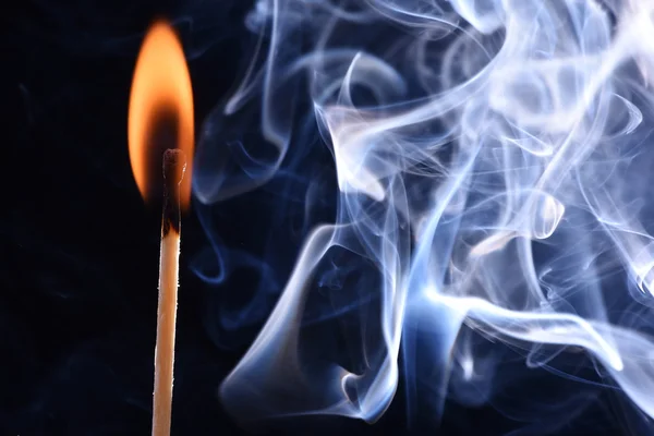 Burnt match in a smoke on a black background. cyan smoke comes out from an extincted match. fire flame match and smoky match