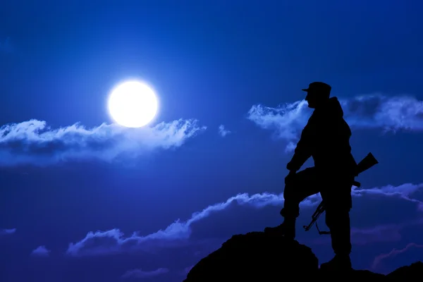 Askeri asker veya memur batımında silahlarla silüeti. atış, elinde silah, renkli gökyüzü, dağ, arka plan