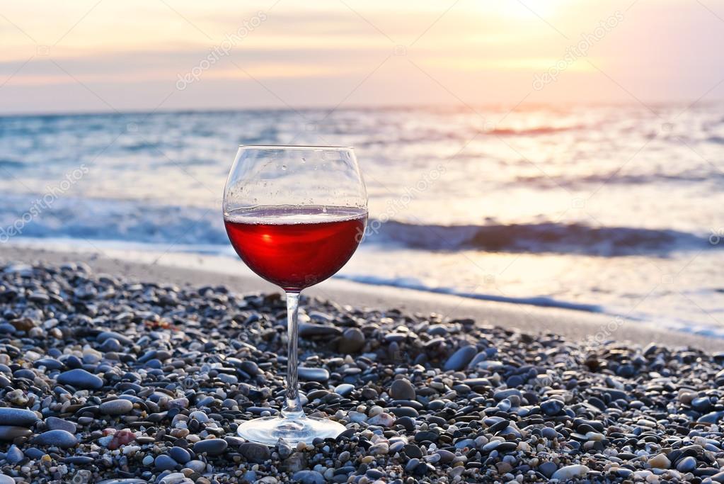 Romantic glass of wine sitting on the beach at colorful sunset, Glass