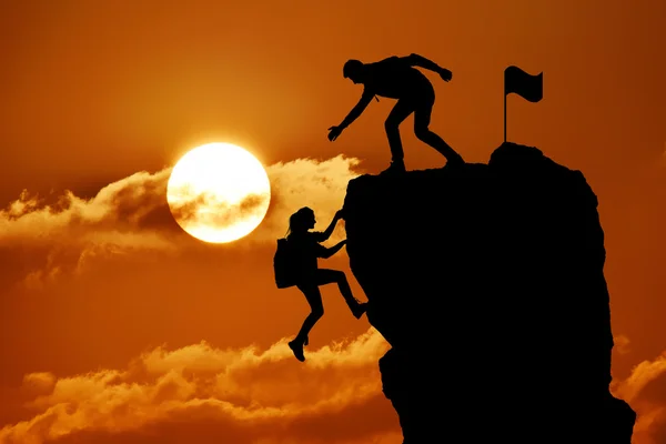 A közös munka csapatmunka két ember ember, és a lány utazók segítik egymást, tetején a hegymászás csapat, a gyönyörű naplemente táj. — Stock Fotó
