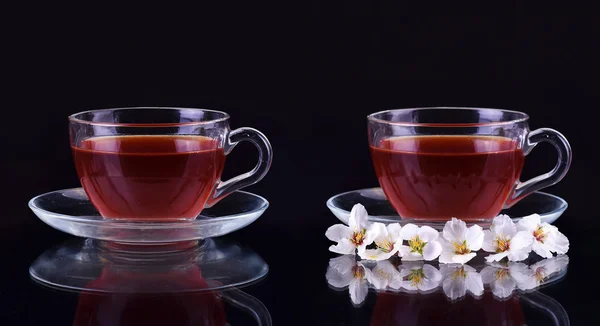 Cup of black tea with cherry branch flowers on dark background — Stock Photo, Image