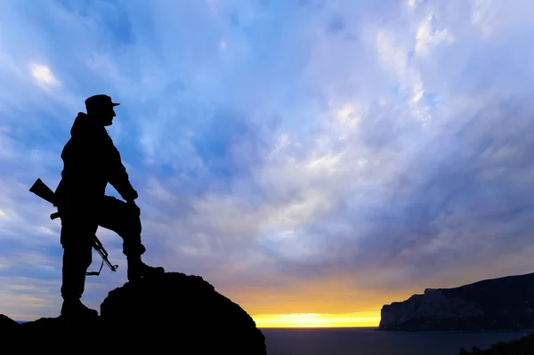 Silhouette of military soldier or officer with weapons at sunset. shot, holding gun, colorful sky, mountain, background — Stock Photo, Image