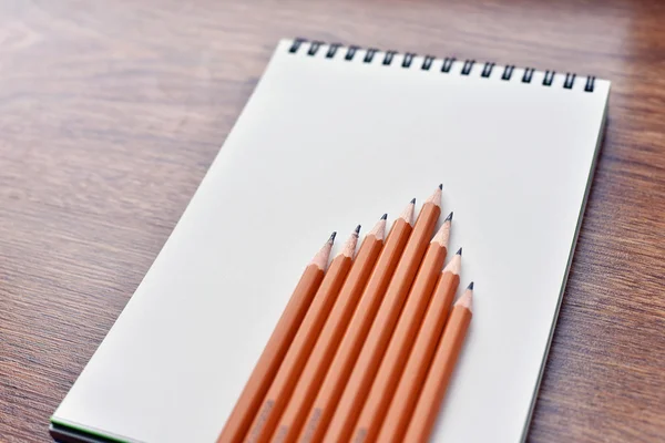 Open blank notebook on grunge wood background with yellow pencils — Stock Photo, Image