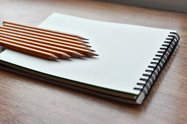 Open blank notebook on grunge wood background with yellow pencils — Stock Photo, Image