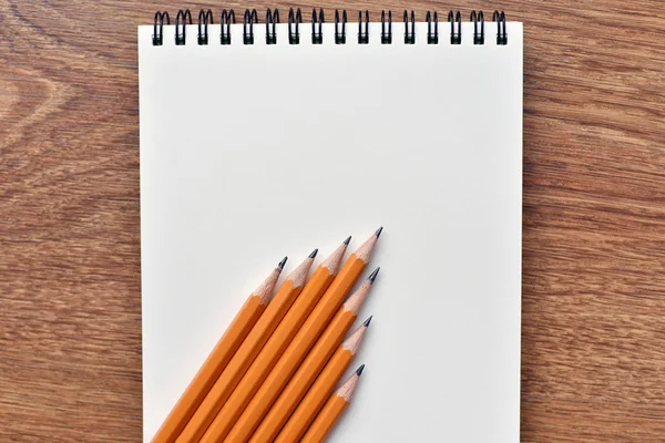 Open blank notebook on grunge wood background with yellow pencils — Stock Photo, Image